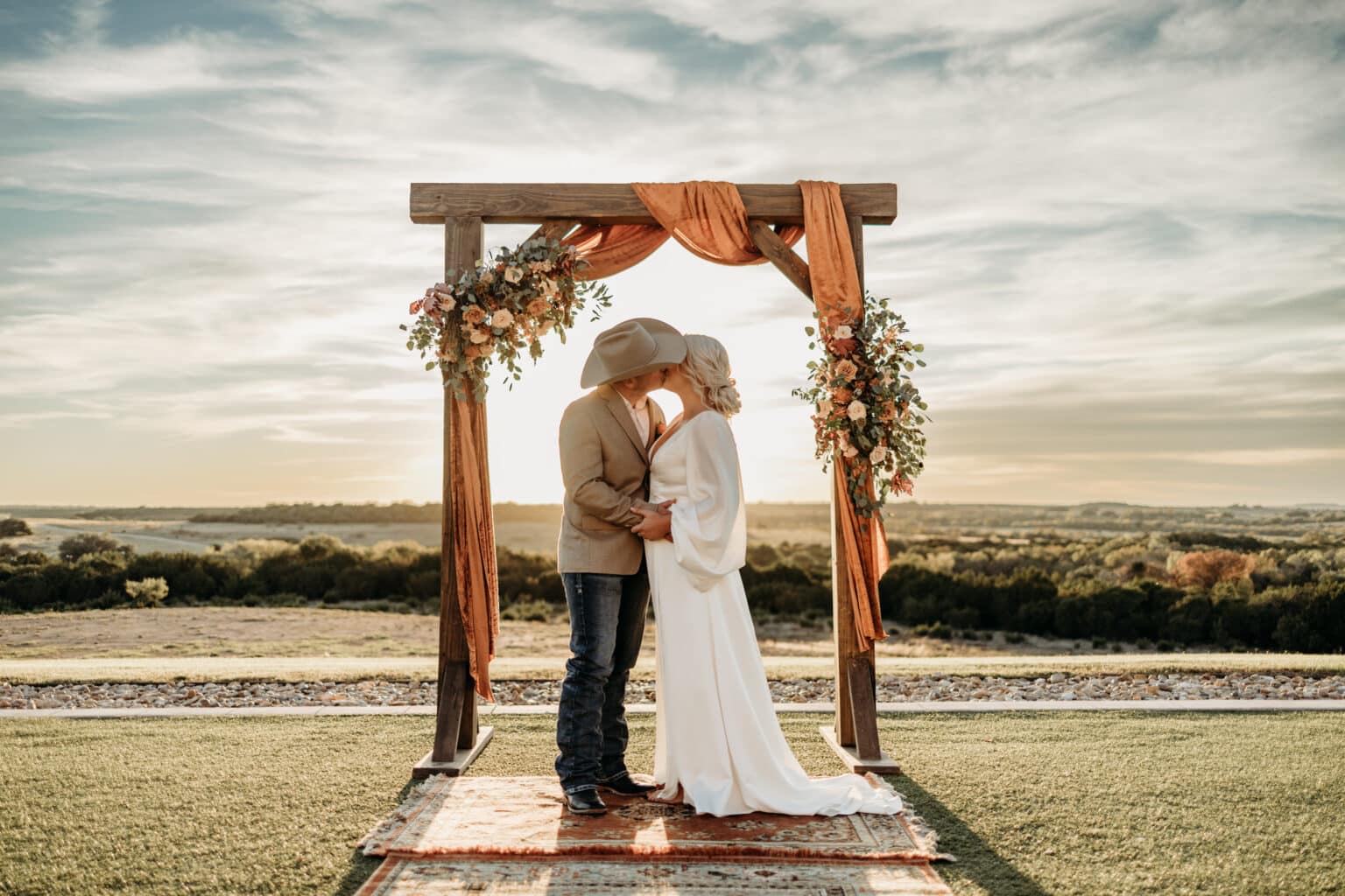 newlyweds kidding under a wooden arbor at texas wedding venue