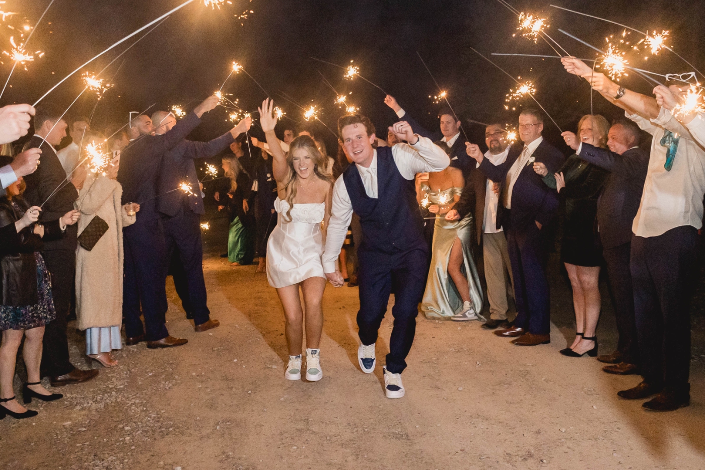 A bride and groom walk beneath a tunnel of sparklers for their grand exit