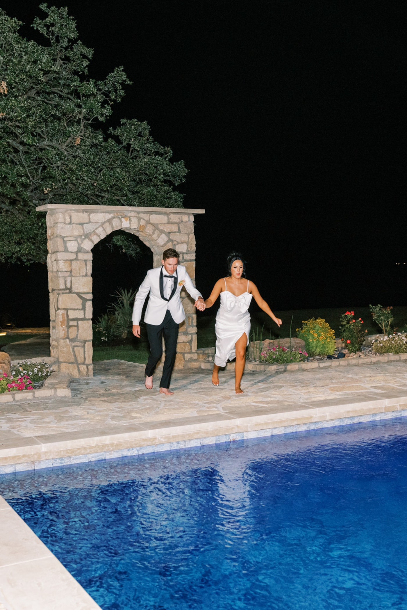 The bride and groom jump in the pool at the Diamond A Ranch after their wedding reception