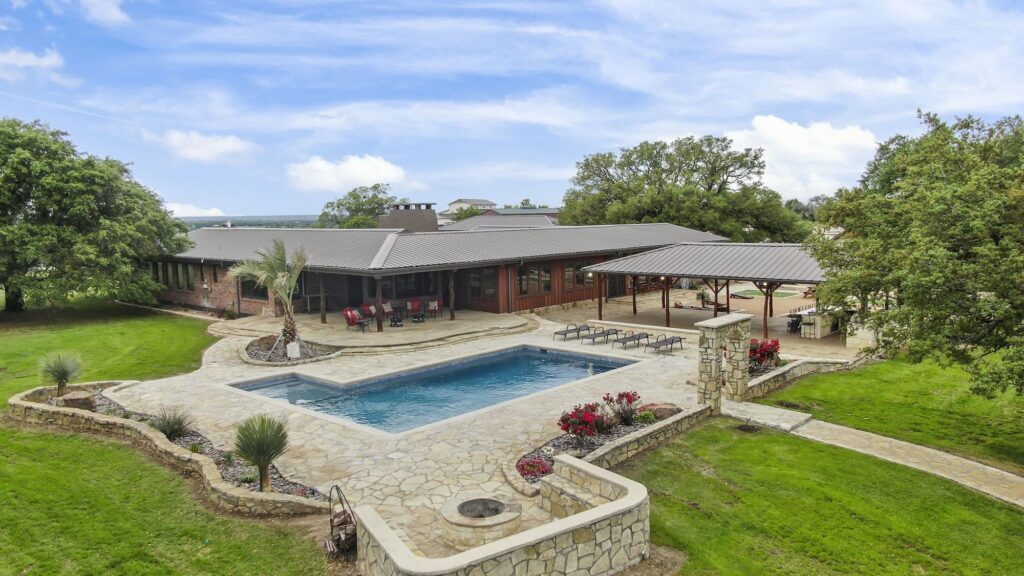 Exterior of the Homestead Quarters lodging at Diamond A Ranch with a pool, fire pit, pavilion, and covered sitting area.
