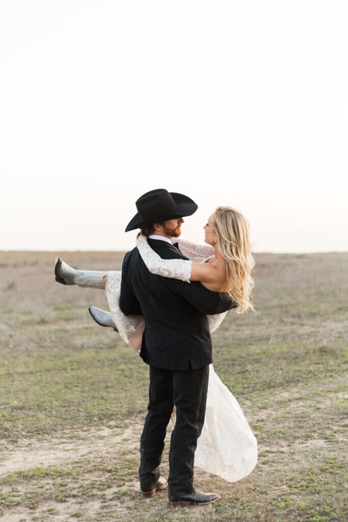 Groom carrying his bride at Diamond A Ranch wedding.