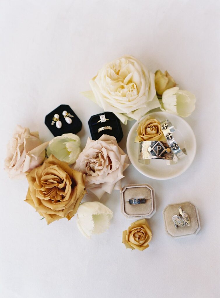 Flat lay of jewelry boxes, ring dish, and roses.