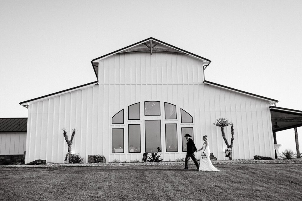A bride and groom walk in front of the cathedral windows of the Diamond A Ranch