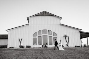 A bride and groom walk in front of the cathedral windows of the Diamond A Ranch