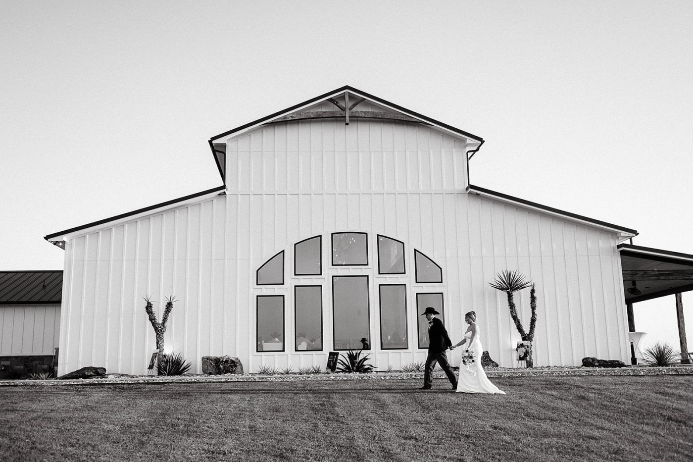 A bride and groom walk in front of the cathedral windows of the Diamond A Ranch