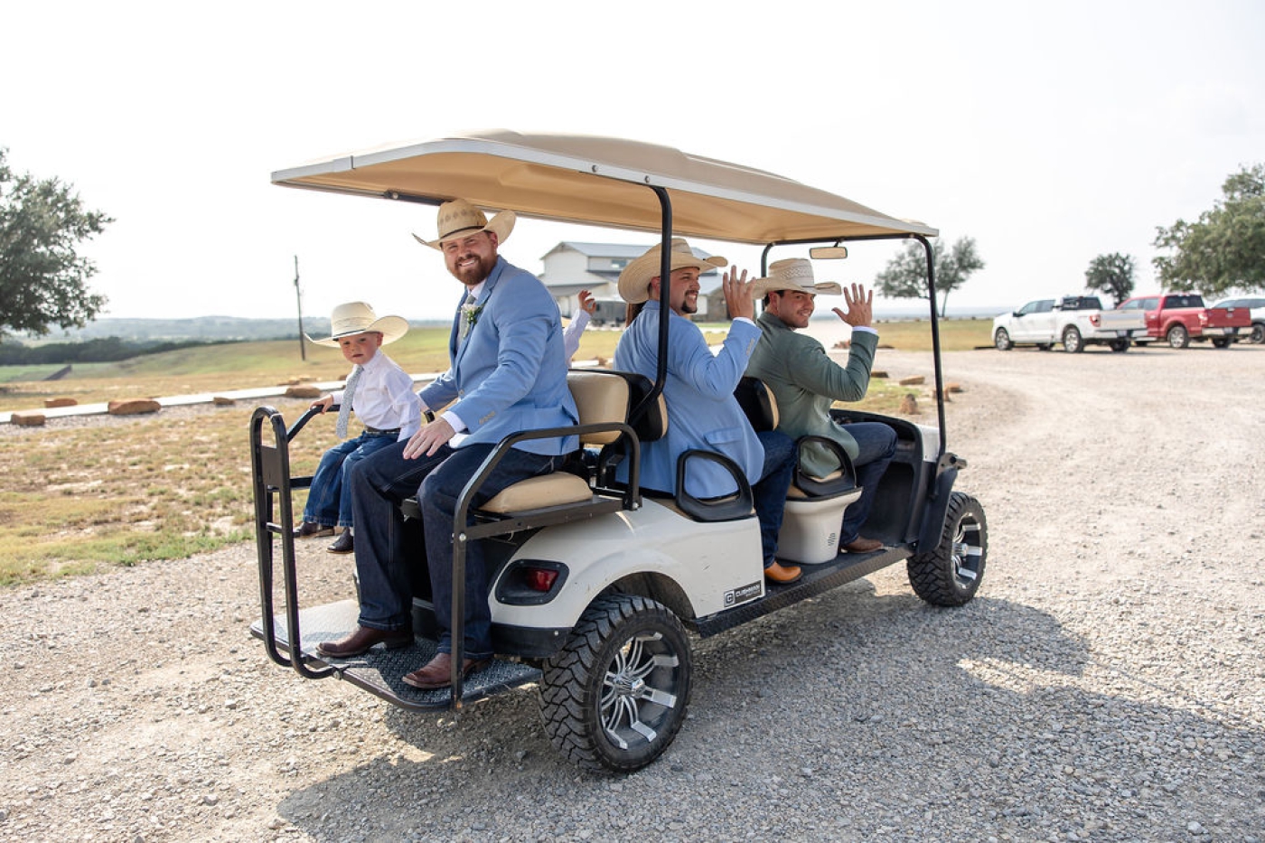 A groom and groomsmen in blue suits in a golf cart on their way to a wedding ceremony