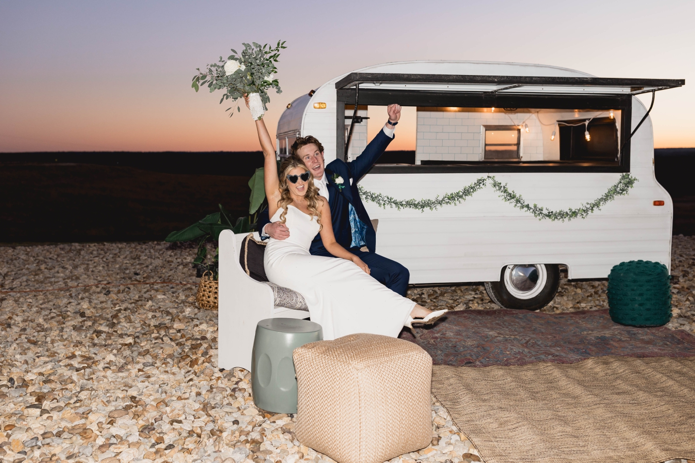 A bride and groom pose in front of a food truck