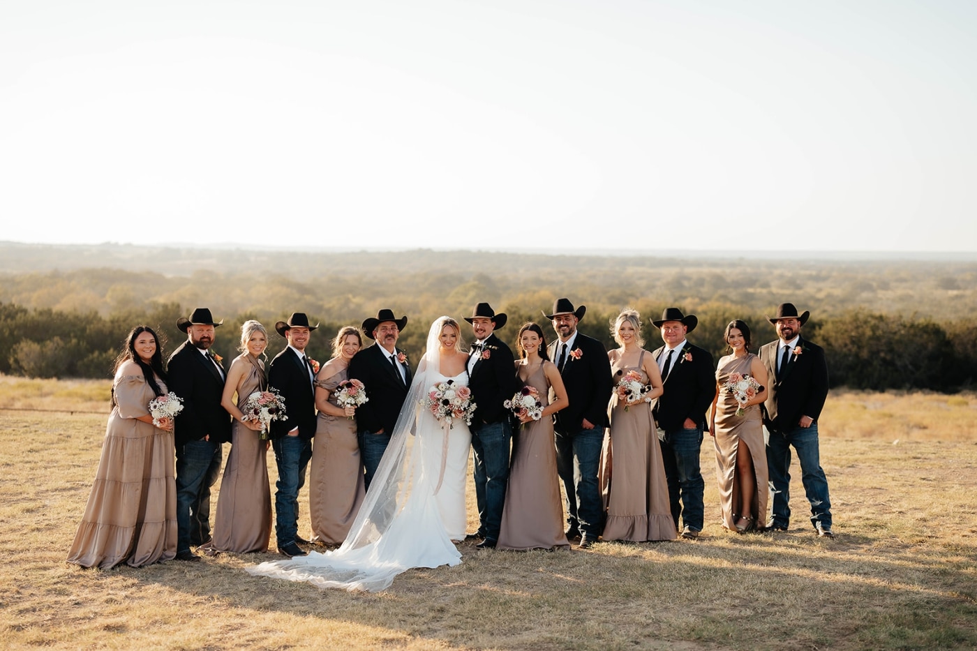 A wedding party of women in beige dresses and men in suit jackets and jeans 