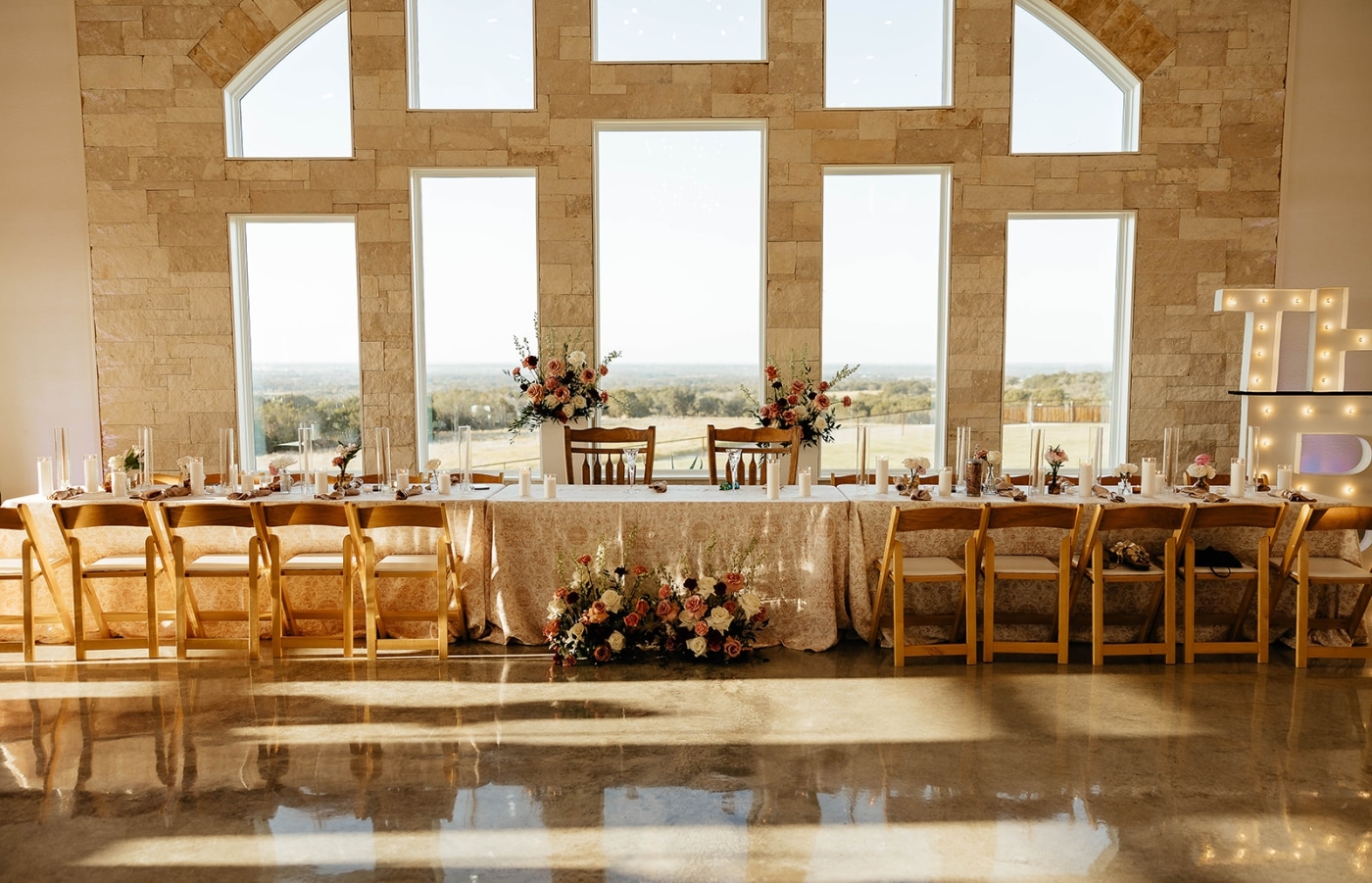 A head table at a wedding reception framed by large cathedral wedding venues 
