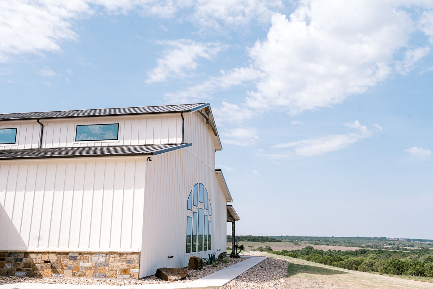 A Texas wedding venue outlined against a blue sky with fluffy white clouds