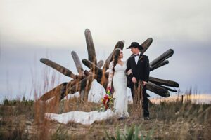 A bride and groom stand in front of an original James Surls sculpture