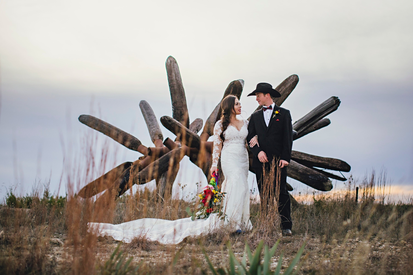 A bride and groom stand in front of an original James Surls sculpture