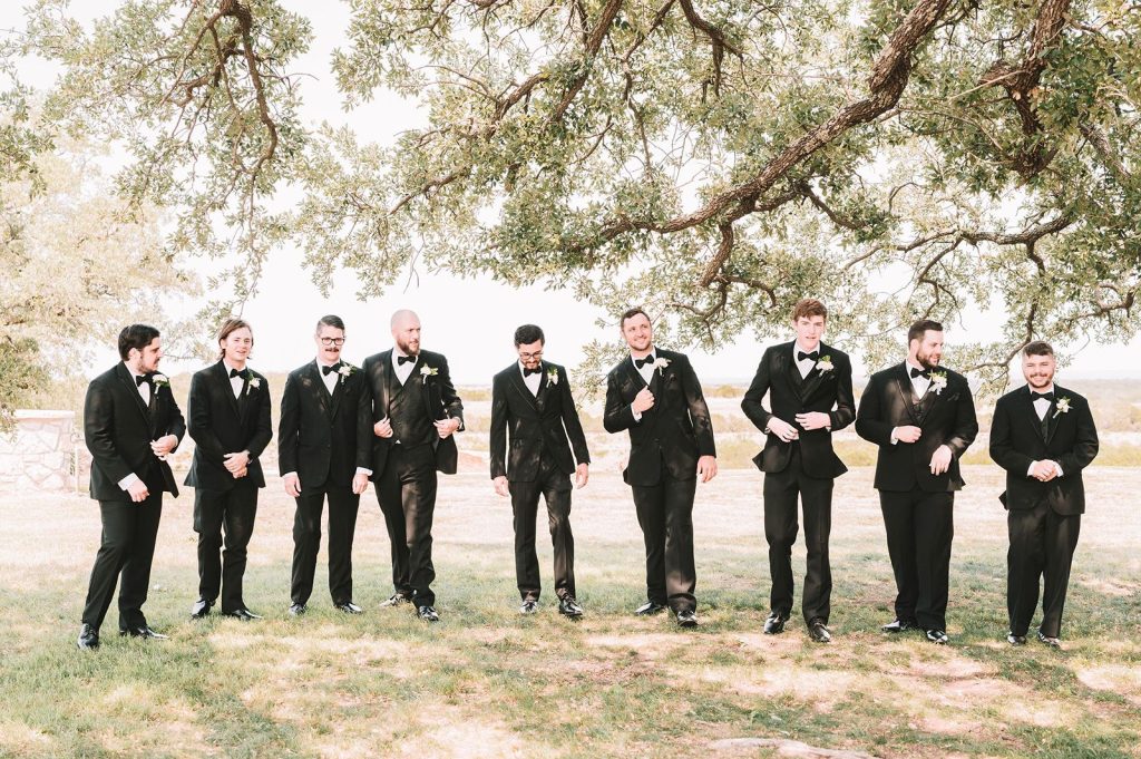 groomsmen-in-live-oak-grove-hill-country groomsmen walking in live oak grove at wedding venue